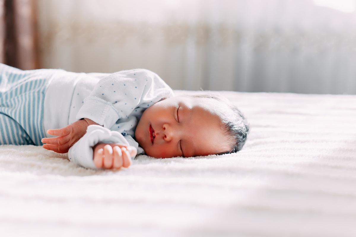 cute newborn brunete baby sleeps lying on soft plaid