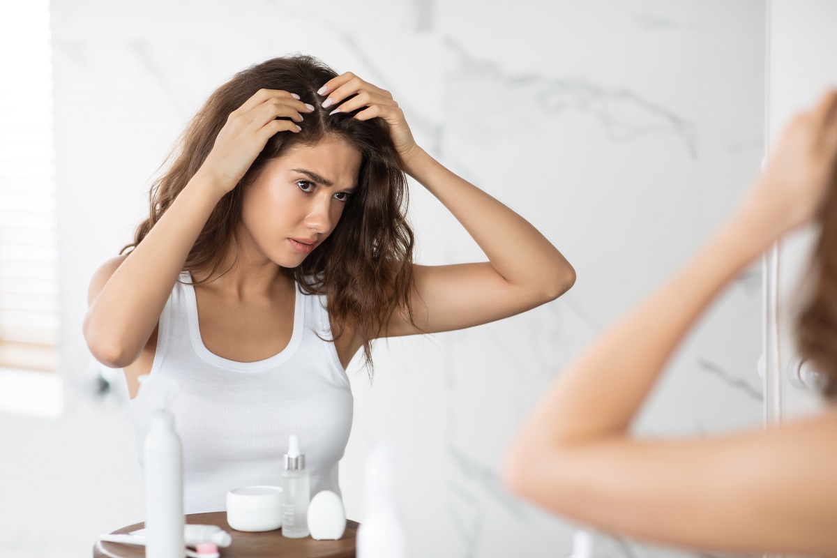 frustrated lady searching hair flakes suffering from dandruff problem indoors