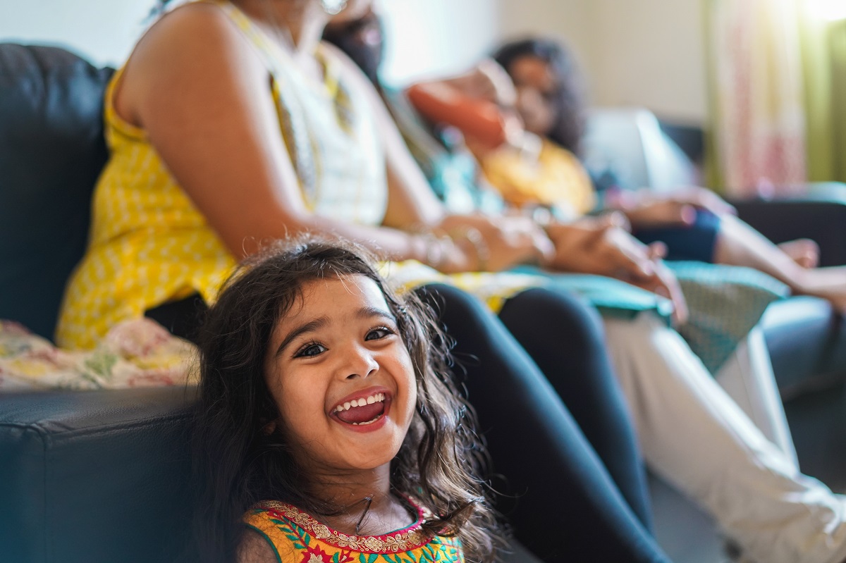 happy indian girl child wearing sari dress sitting on sofa with