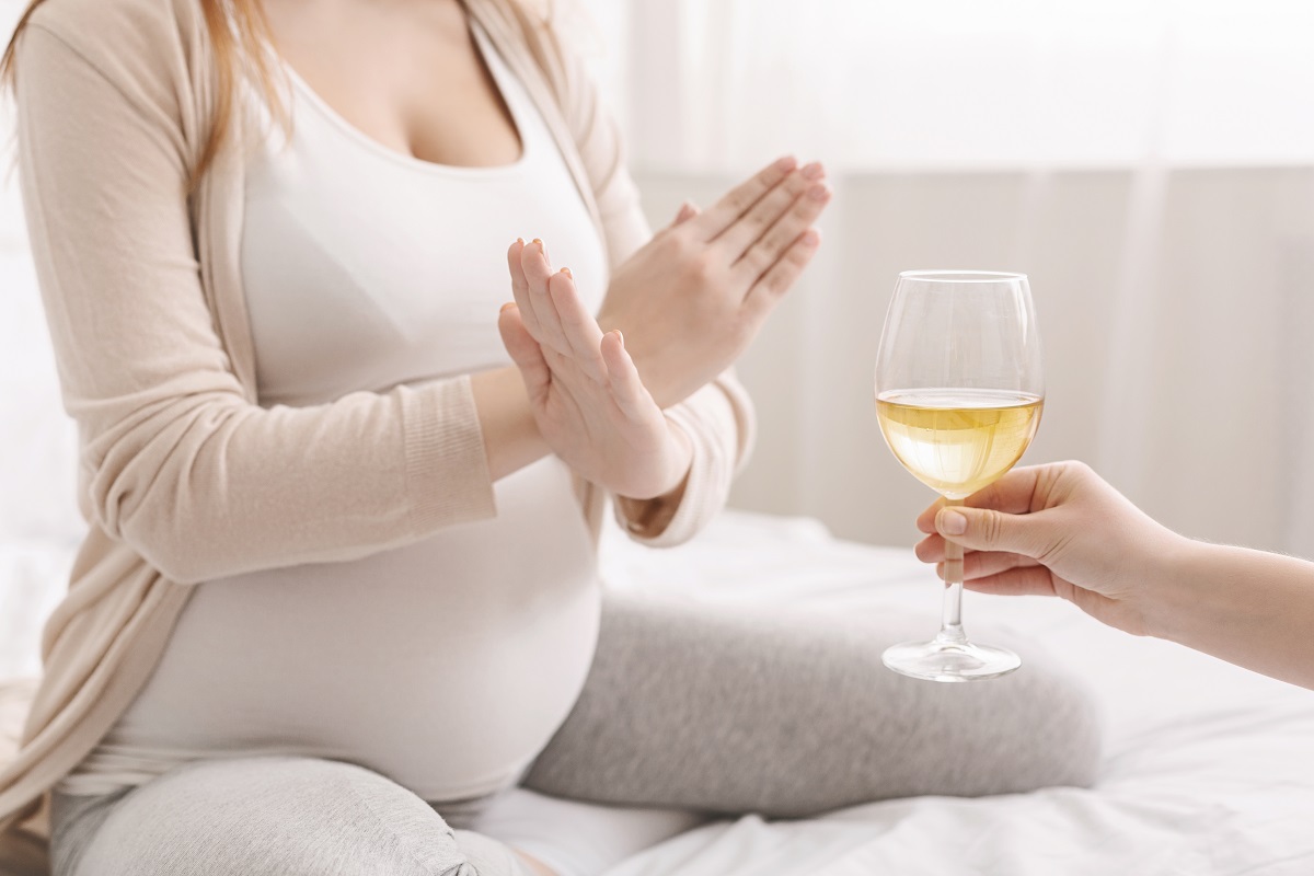 pregnant woman with crossed hands refusing to drink wine