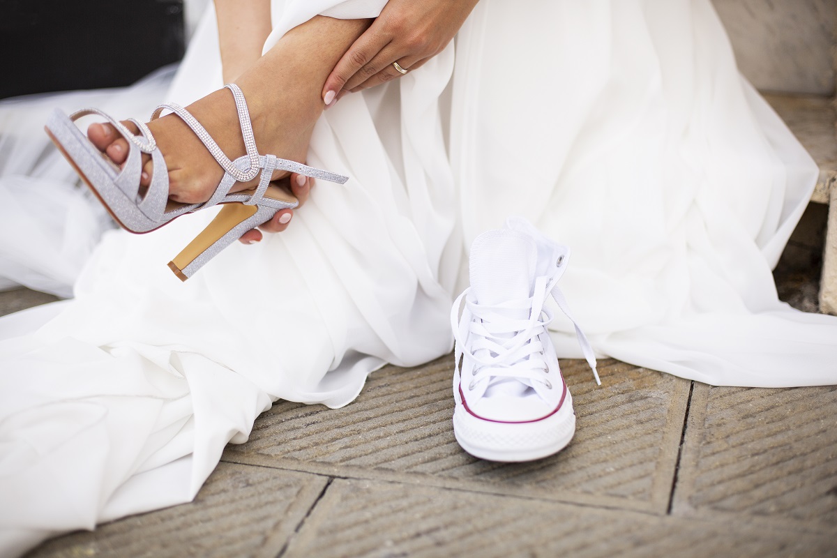 bride changing her formal shoes with comfortable white sneakers