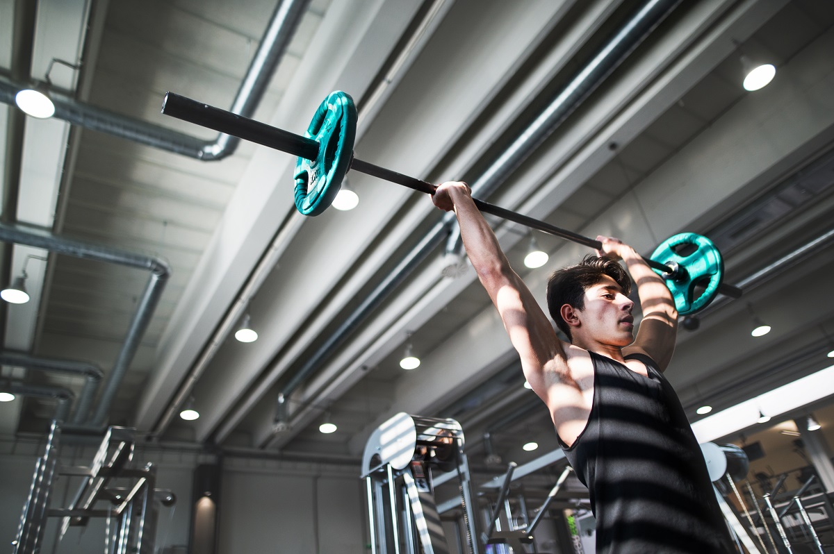 fit young man in gym working out, lifting barbell. copy space.
