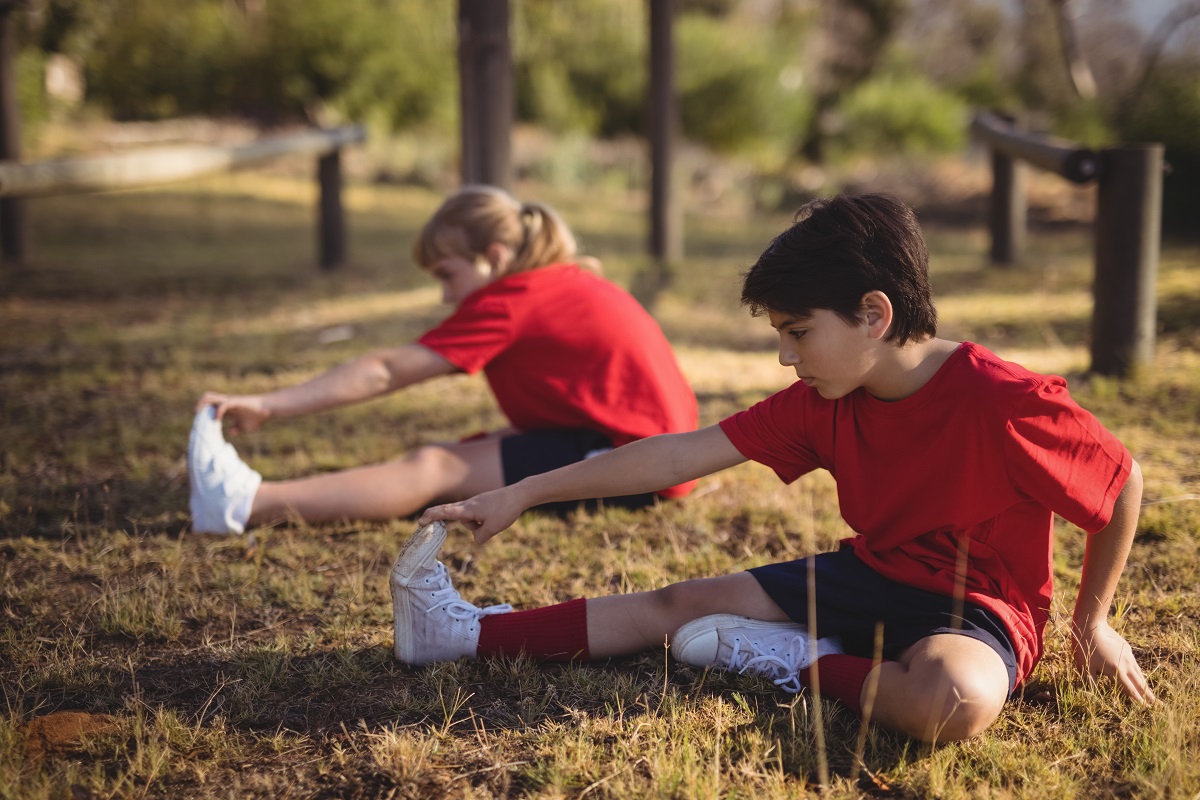 kids performing stretching exercise during obstacle course in boot camp