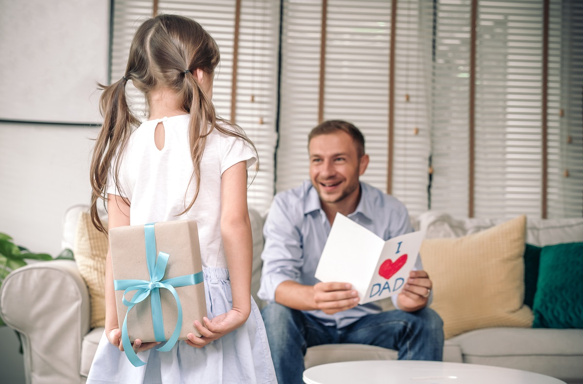 cute little girl is giving card her handsome father and surprisi