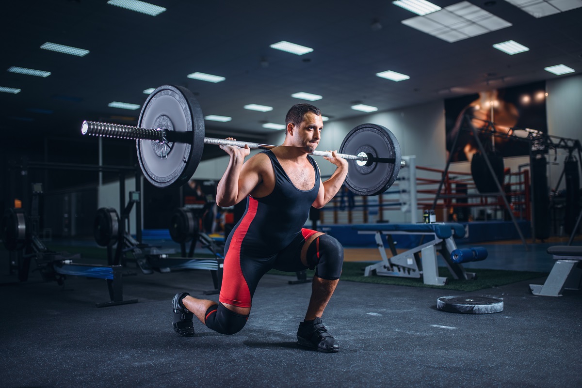 weight lifter doing squats with a barbell in gym